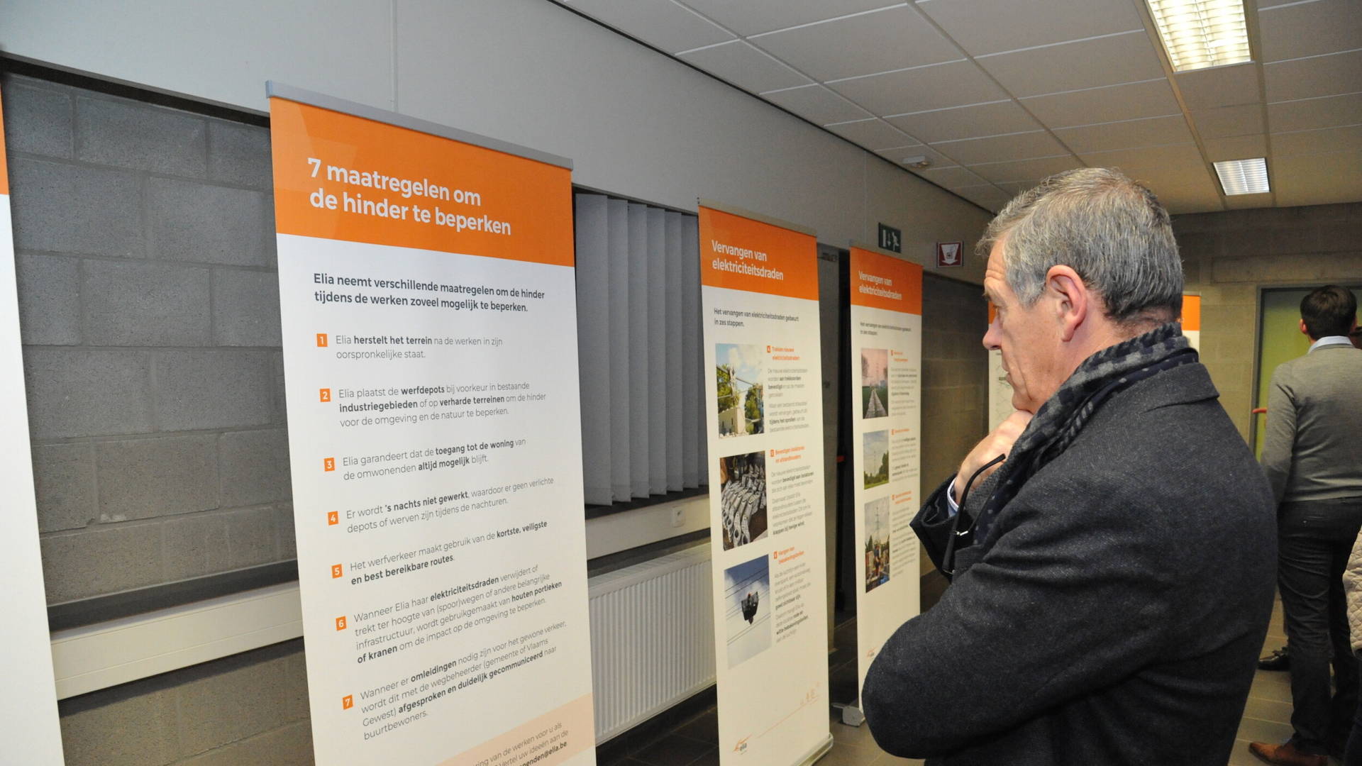 Elia infoavond. Roll-up banners met informatie over het project. Bezoekers lezen de informatie.