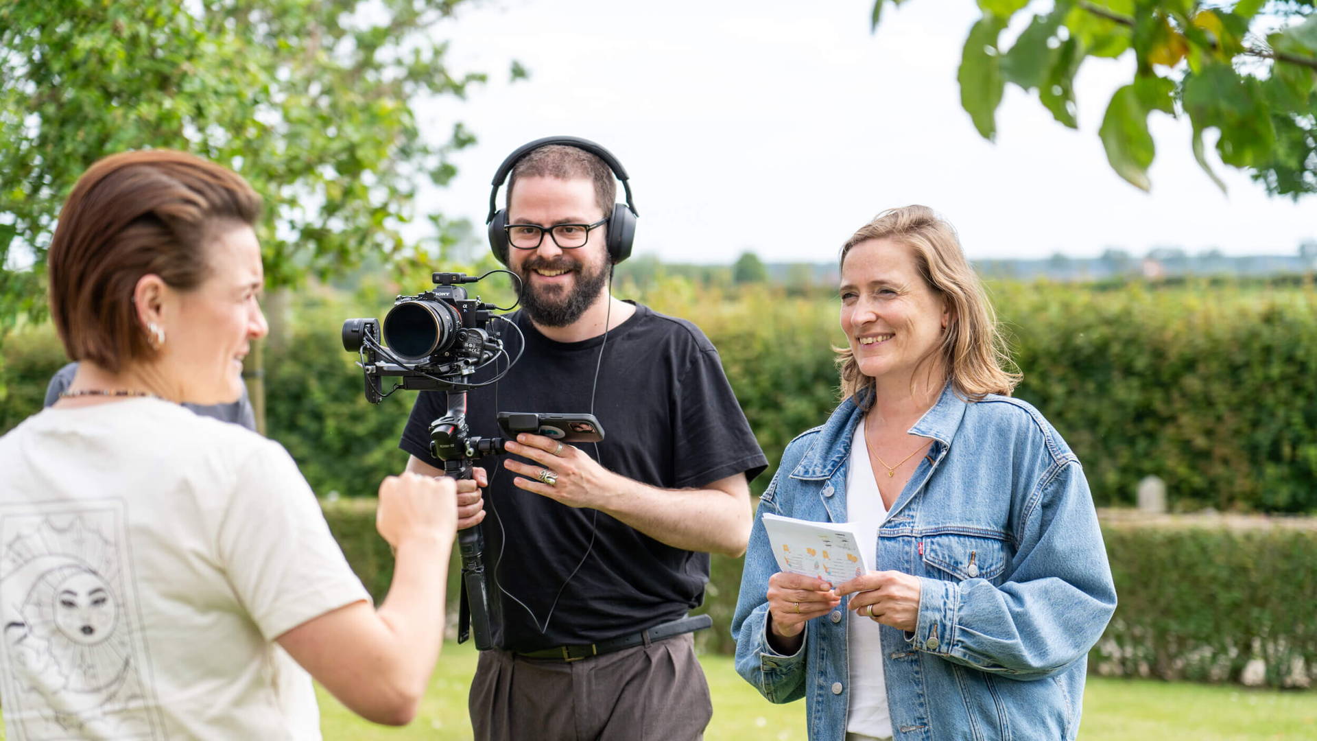 Medewerker Gil filmt een interview met medecollega. Op het hoofd draagt hij een hoofdtelefoon voor het geluid.