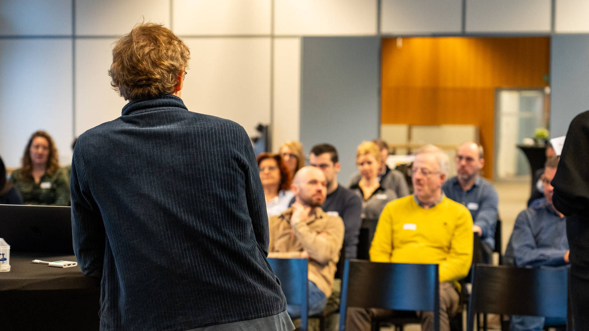 Lors d'une séance de travail sur le projet HOV Hasselt-Maastricht, une personne en charge du projet donne une présentation dans une salle devant plusieurs personnes pour présenter le projet et les travaux à venir.