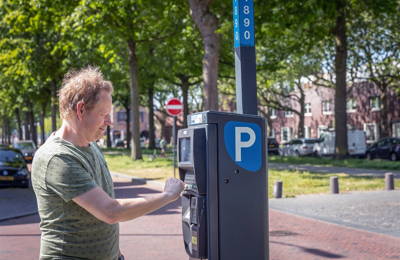 Man betaalt voor parkeren bij een parkeerautomaat in Breda